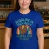 Quiet and Dim Migraine Royal Blue Short Sleeve Tee. Image has coffee shop / restaurant background. Model is Straight Fit (S-L) Female.