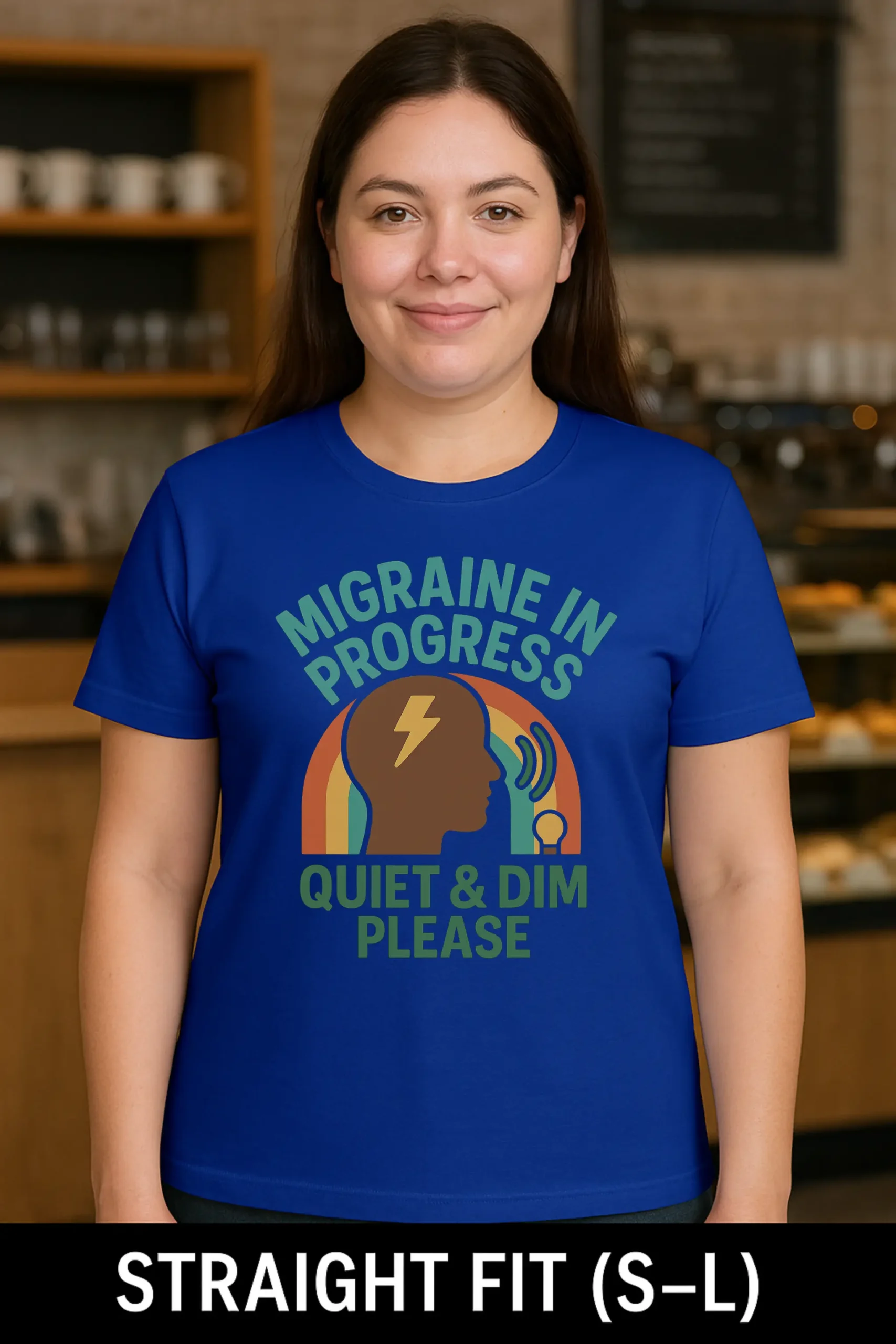 Quiet and Dim Migraine Royal Blue Short Sleeve Tee. Image has coffee shop / restaurant background. Model is Straight Fit (S-L) Female.