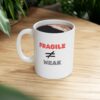 "Fragile Not Equal Weak" Ceramic Mug on a wood grain counter or desk