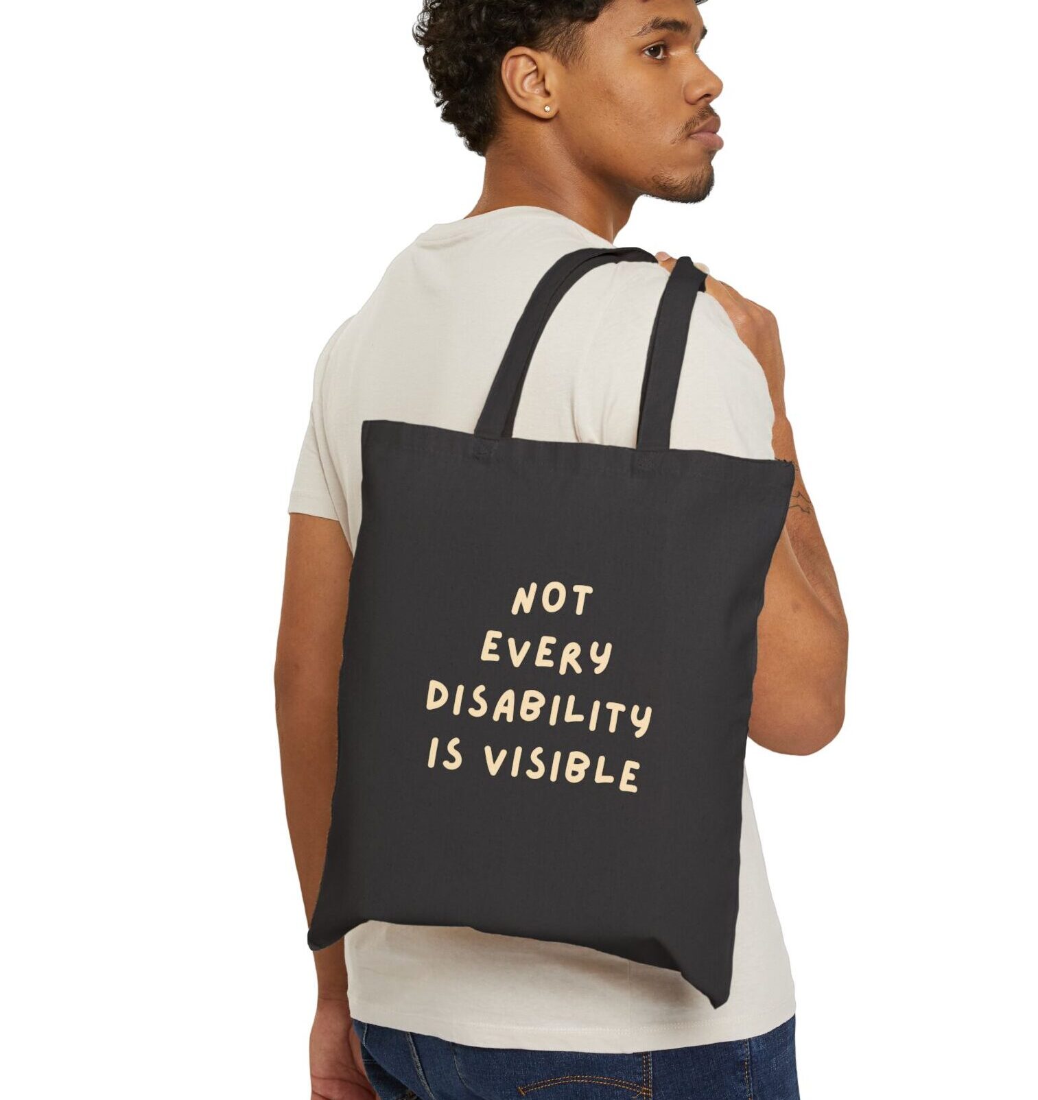 “Not Every Disability Is Visible” Canvas Tote in Black held by a male model
